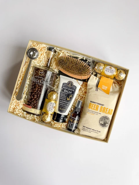 Black gift box with bath, body and grooming treats arranged in black crinkle paper